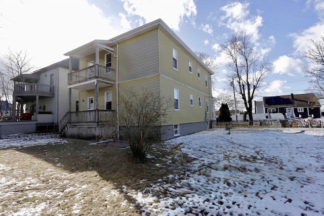 snow covered back of property featuring a balcony