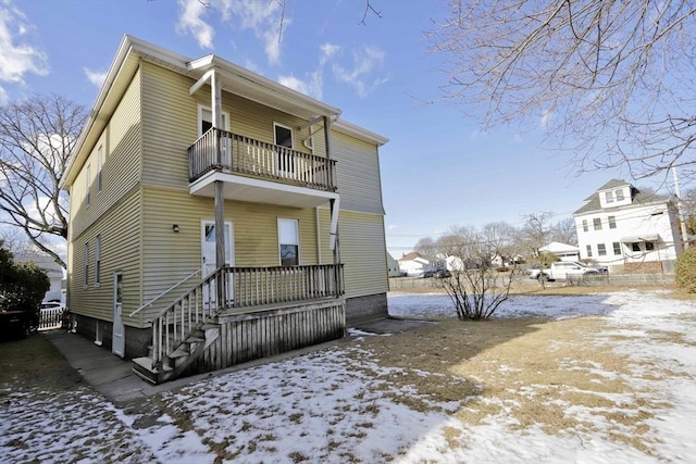 snow covered rear of property with a balcony