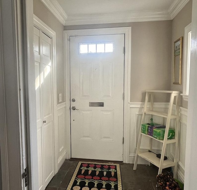 doorway to outside with a wainscoted wall, dark tile patterned floors, and ornamental molding