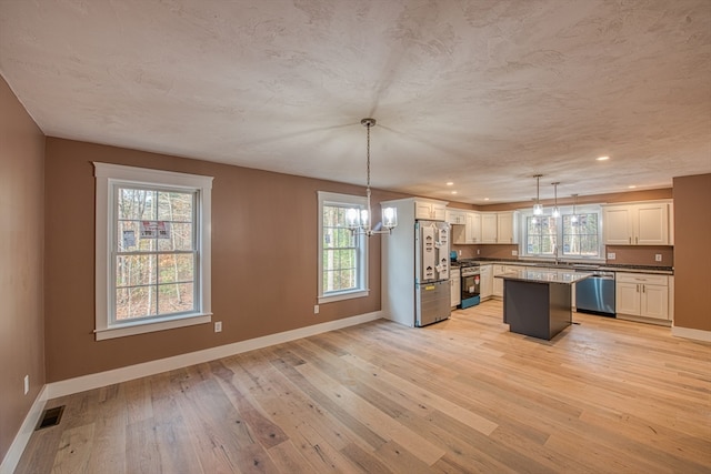 kitchen with stainless steel appliances, a wealth of natural light, and decorative light fixtures