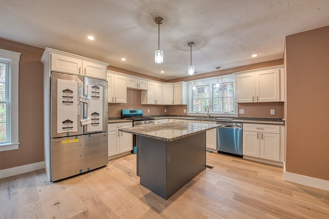 kitchen featuring hanging light fixtures, light wood-type flooring, appliances with stainless steel finishes, and a center island