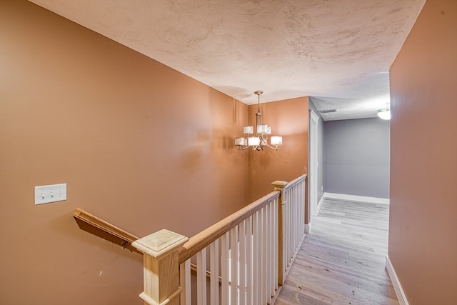 hallway featuring an inviting chandelier and light hardwood / wood-style flooring