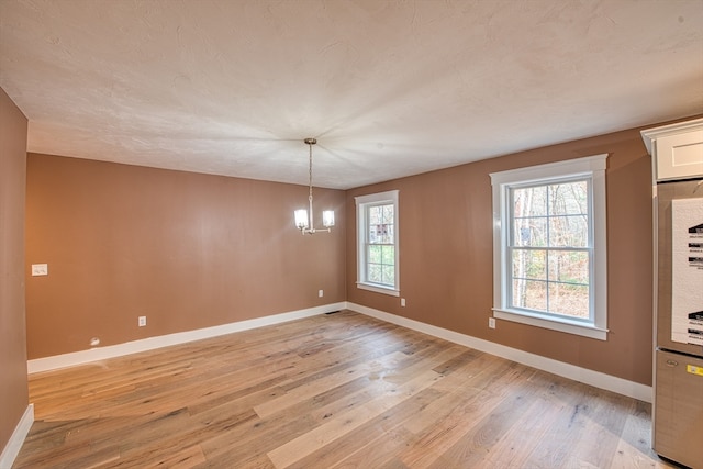 unfurnished dining area featuring an inviting chandelier, light hardwood / wood-style floors, and plenty of natural light