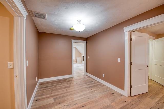 empty room featuring light hardwood / wood-style floors and a textured ceiling