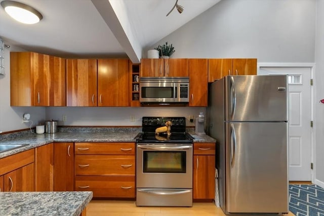 kitchen with stainless steel appliances, brown cabinetry, lofted ceiling, and light wood-type flooring
