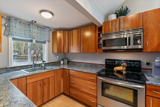 kitchen with appliances with stainless steel finishes, a sink, and brown cabinetry