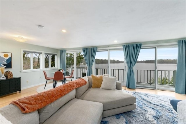 living room with baseboards, a water view, wood finished floors, and recessed lighting