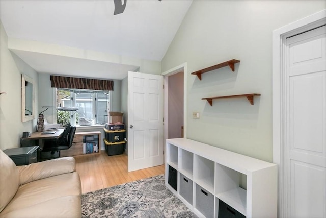 living area featuring wood finished floors, vaulted ceiling, an office area, and a ceiling fan