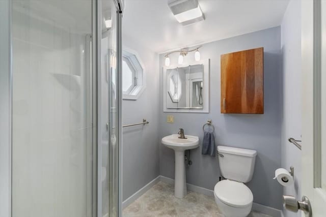 bathroom with a shower stall, toilet, and baseboards