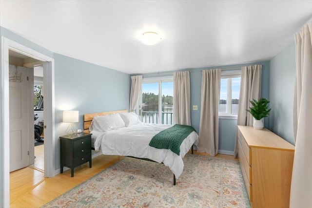 bedroom with light wood-type flooring and a water view
