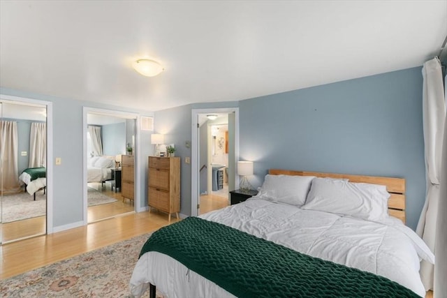 bedroom with wood finished floors, multiple closets, and baseboards