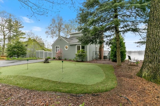 view of yard featuring an area to practice putting, fence, and a water view