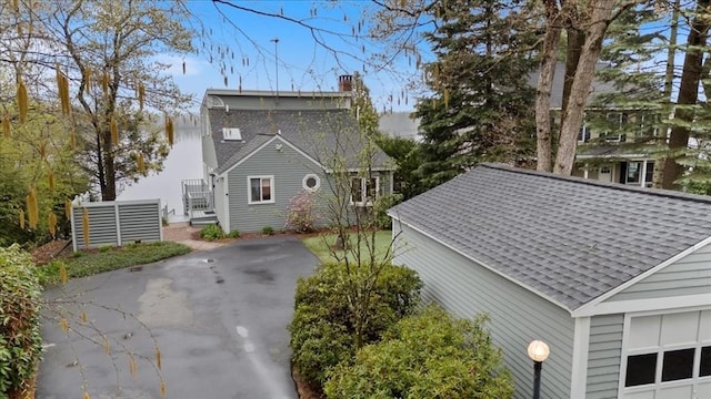 view of property exterior with a chimney and a shingled roof