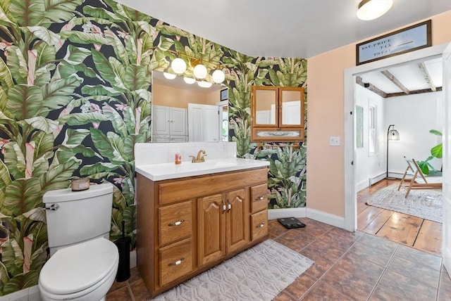 bathroom featuring vanity, baseboards, wallpapered walls, tile patterned flooring, and toilet