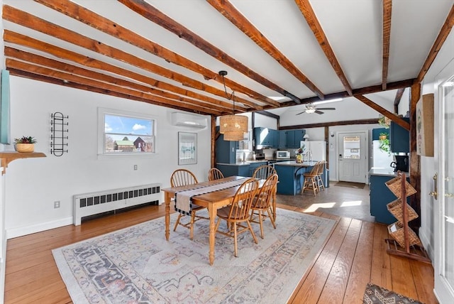 dining space with beam ceiling, a wall mounted AC, radiator heating unit, wood-type flooring, and baseboards