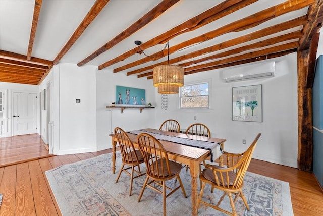 dining area featuring hardwood / wood-style floors, a wall unit AC, beamed ceiling, and baseboards