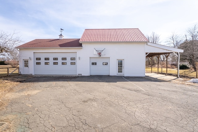 view of front facade with an outbuilding, metal roof, a carport, and fence