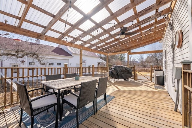 wooden deck with grilling area, outdoor dining area, and ceiling fan