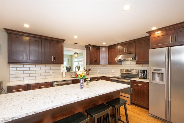 215 Alida Rd, Braintree, MA 02184 - kitchen featuring stainless steel appliances, under cabinet range hood, a kitchen bar, backsplash, and dark brown cabinetry