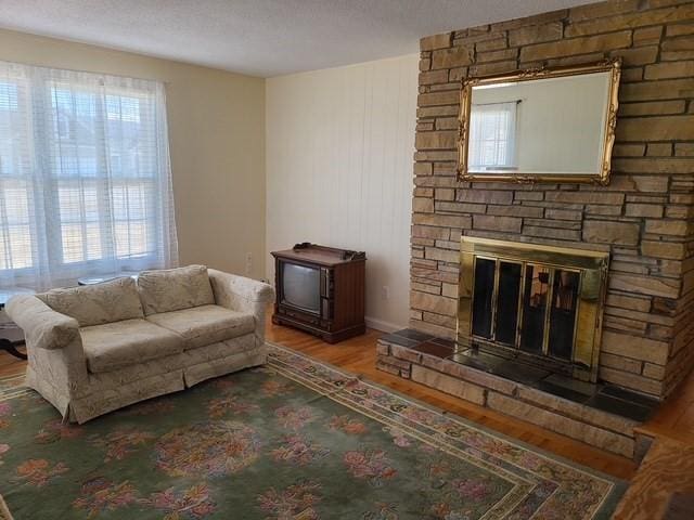 living area featuring a stone fireplace and wood finished floors