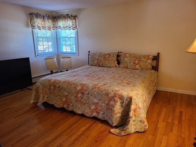 bedroom featuring wood finished floors, baseboards, and baseboard heating