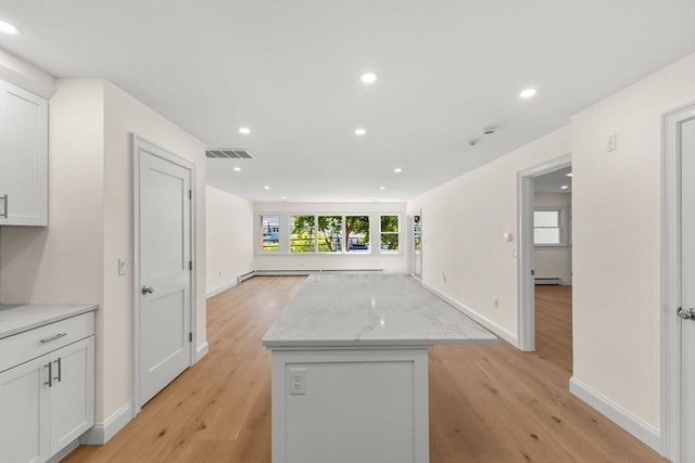kitchen with a kitchen island, light wood-style flooring, open floor plan, white cabinetry, and recessed lighting