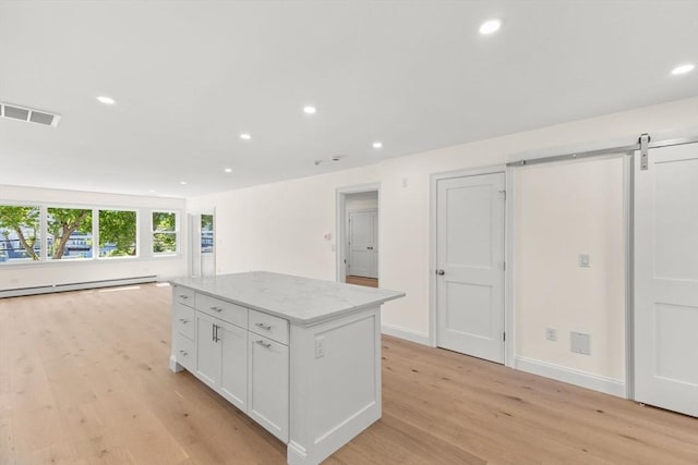 kitchen featuring baseboard heating, a kitchen island, light wood-style floors, open floor plan, and recessed lighting