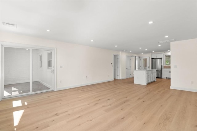unfurnished living room with recessed lighting, light wood-style floors, and baseboards