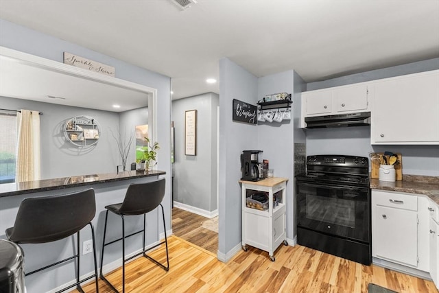 221 Oak St Unit 223, Brockton, MA 02302 - kitchen with black electric range, under cabinet range hood, white cabinets, light wood-style flooring, and a kitchen bar