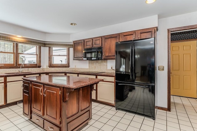 kitchen with a kitchen island, light stone counters, black appliances, a sink, and light tile patterned flooring