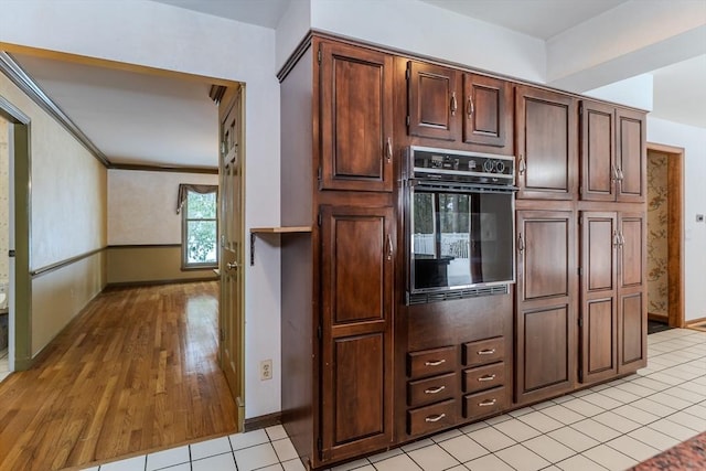 kitchen with baseboards, light wood-style flooring, oven, and crown molding