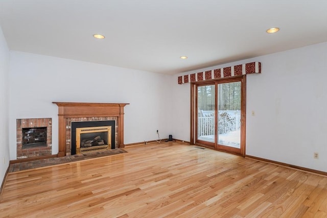 unfurnished living room featuring wood finished floors, recessed lighting, a fireplace with flush hearth, and baseboards