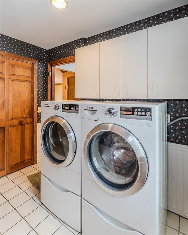 washroom with washer and clothes dryer, light tile patterned flooring, cabinet space, and wallpapered walls