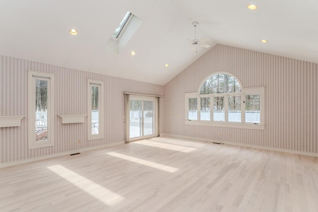 unfurnished living room featuring a skylight, light wood-style flooring, and wallpapered walls