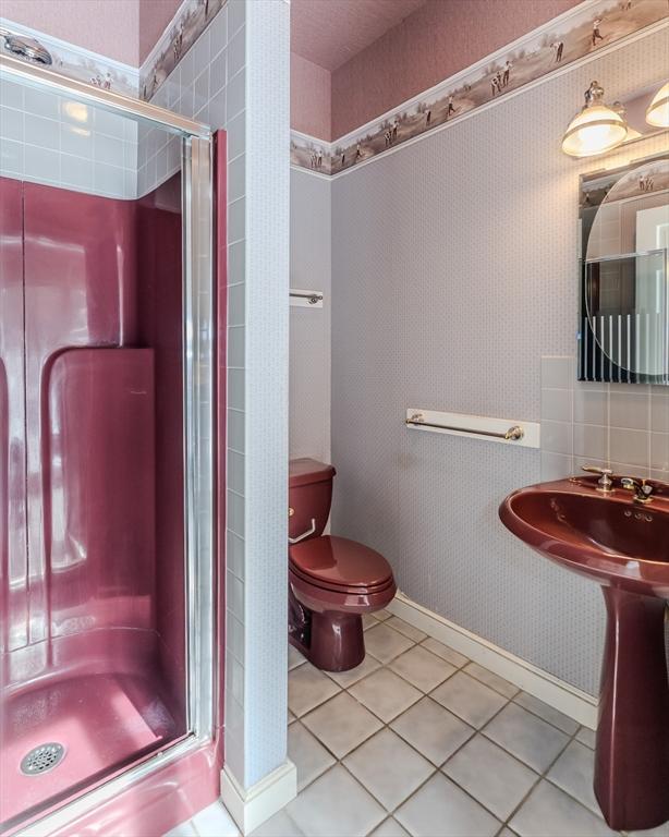 bathroom featuring tile patterned flooring, a shower stall, toilet, and wallpapered walls