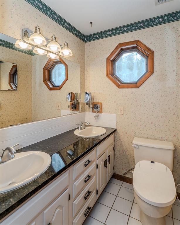 bathroom featuring toilet, wallpapered walls, a sink, and tile patterned floors