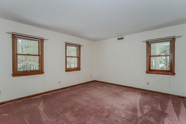 spare room with carpet flooring, visible vents, and baseboards