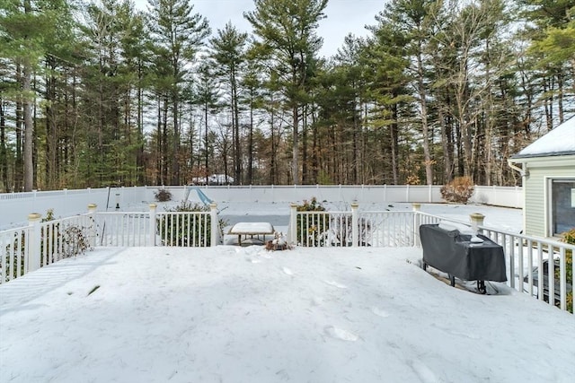 snow covered deck with a fenced backyard and grilling area