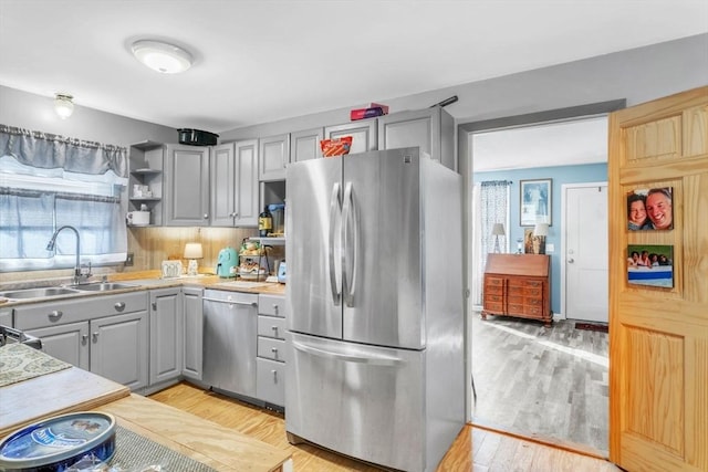 kitchen featuring light hardwood / wood-style flooring, sink, gray cabinets, and appliances with stainless steel finishes