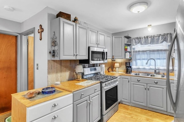 kitchen featuring tasteful backsplash, stainless steel appliances, sink, and gray cabinetry