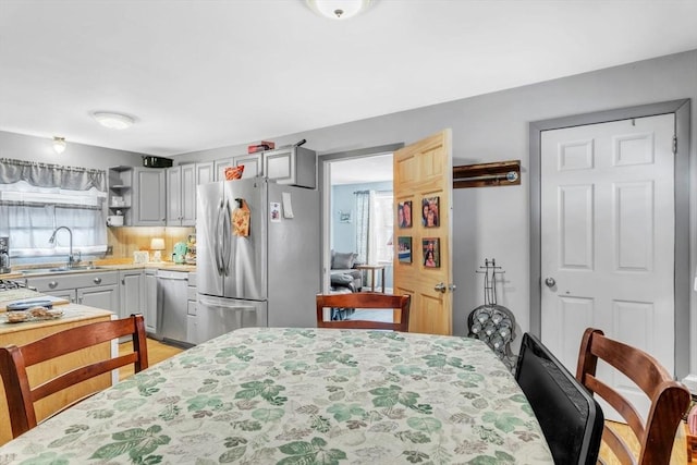 kitchen with appliances with stainless steel finishes, sink, decorative backsplash, and gray cabinetry