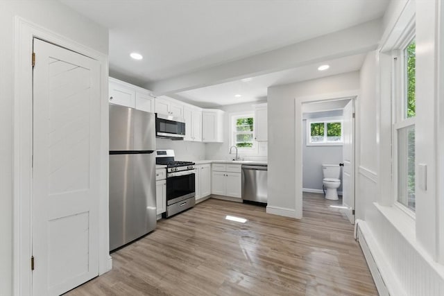 515 Front St, Weymouth, MA 02188 - kitchen featuring stainless steel appliances, baseboard heating, white cabinets, light countertops, and light wood finished floors