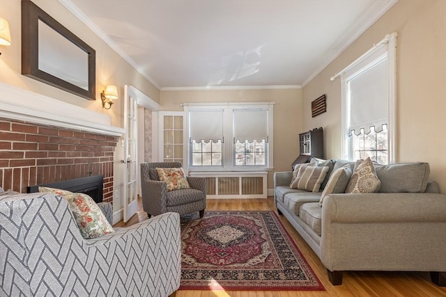 living room with crown molding, a brick fireplace, radiator, and light hardwood / wood-style flooring