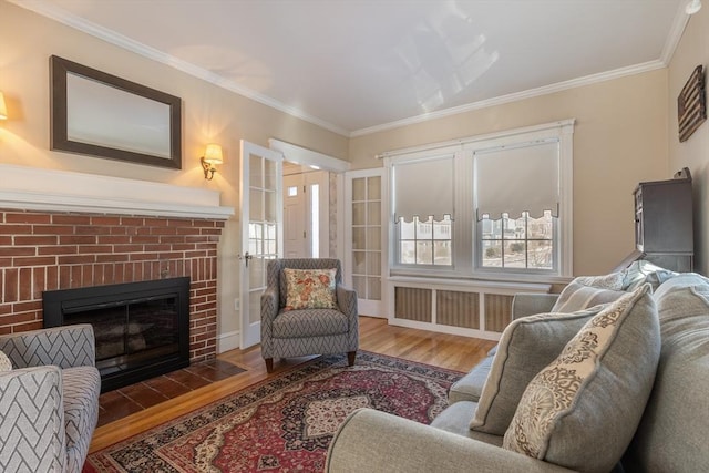 sitting room featuring hardwood / wood-style flooring, radiator heating unit, crown molding, and a brick fireplace