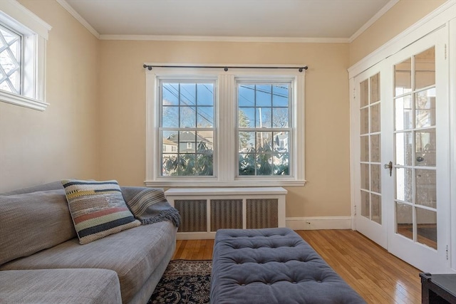 living area featuring hardwood / wood-style flooring, radiator heating unit, and crown molding