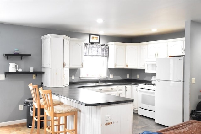 kitchen featuring white cabinetry, sink, white appliances, and kitchen peninsula