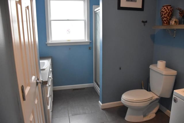 bathroom featuring a shower with shower door, vanity, toilet, washing machine and dryer, and tile patterned floors