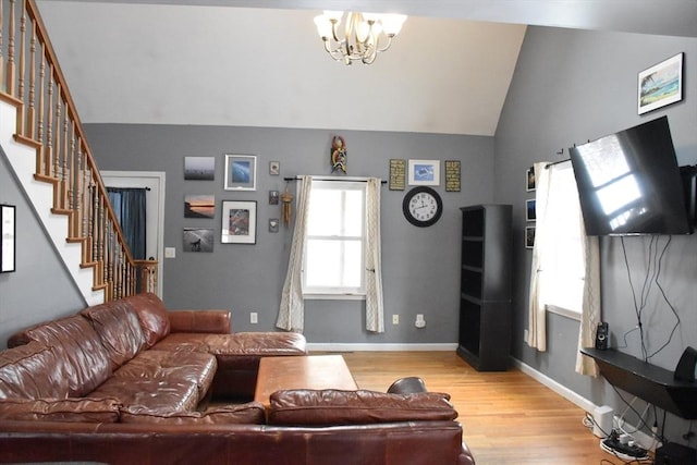 living room featuring lofted ceiling, light hardwood / wood-style floors, and a notable chandelier