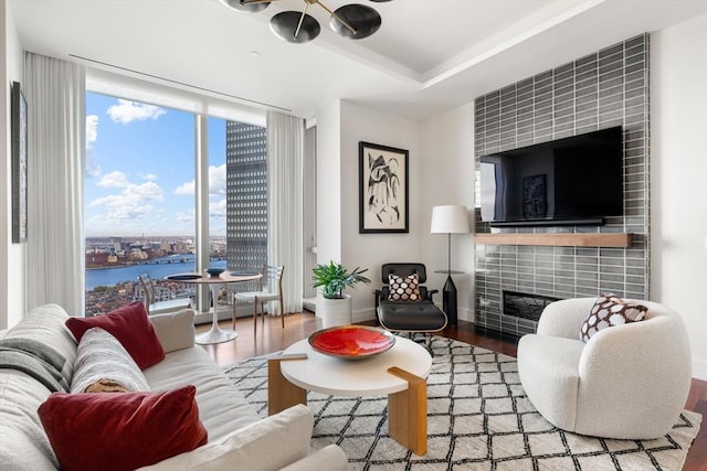 living room with a water view, a wall of windows, a fireplace, and hardwood / wood-style floors