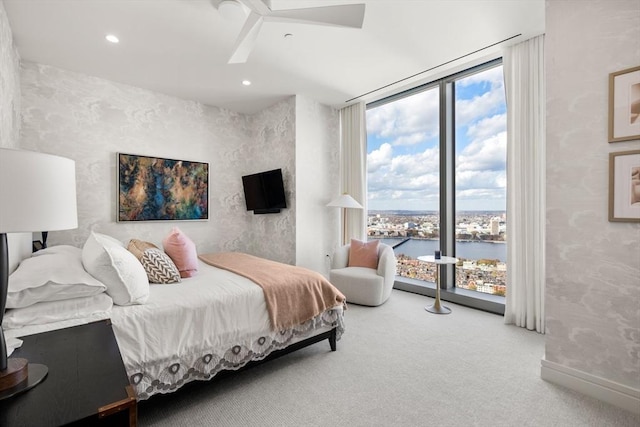 bedroom featuring ceiling fan, a wall of windows, and carpet floors